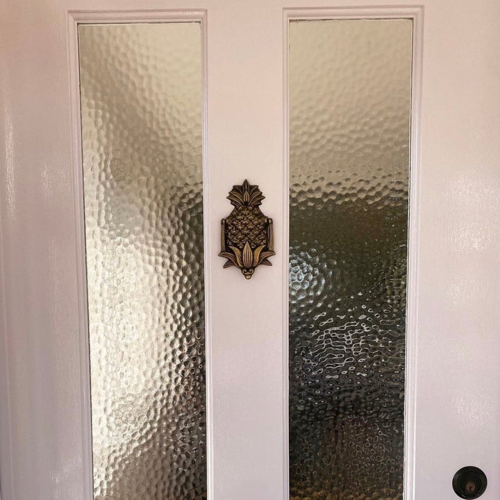 Antique pineapple door knocker on door by Ocean Luxe